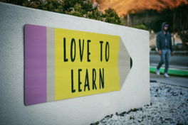 love-to-learn-pencil-signage-on-wall-near-walking-man.jpg love to learn pencil signage on wall near walking man
